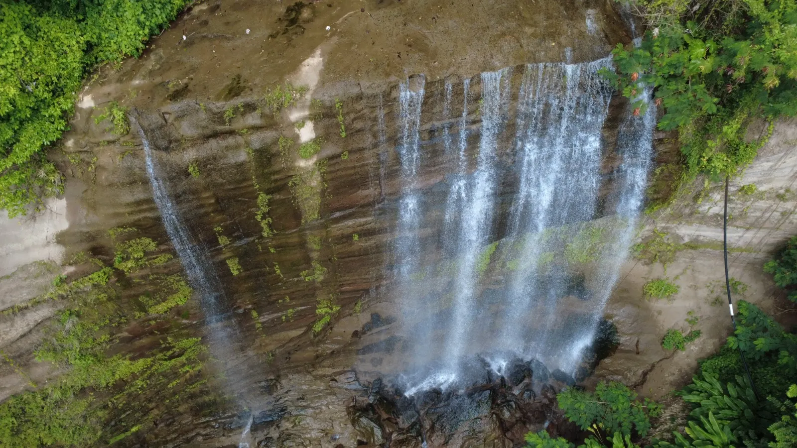 Drone shot of a cascading rainforest waterfall